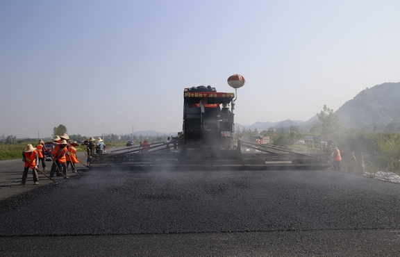 2019年8月，宜春經開區(qū)S311路面攤鋪現(xiàn)場，工友們輔助路面兩側的分料、補窩等作業(yè)